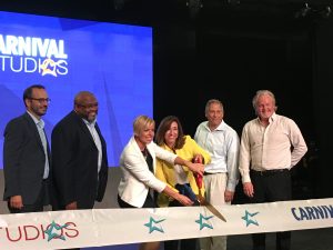 Christine Duffy, in yellow, cutting the ribbon for the new Carnival facility with Sarah Beth Reno, vice president of entertainment.