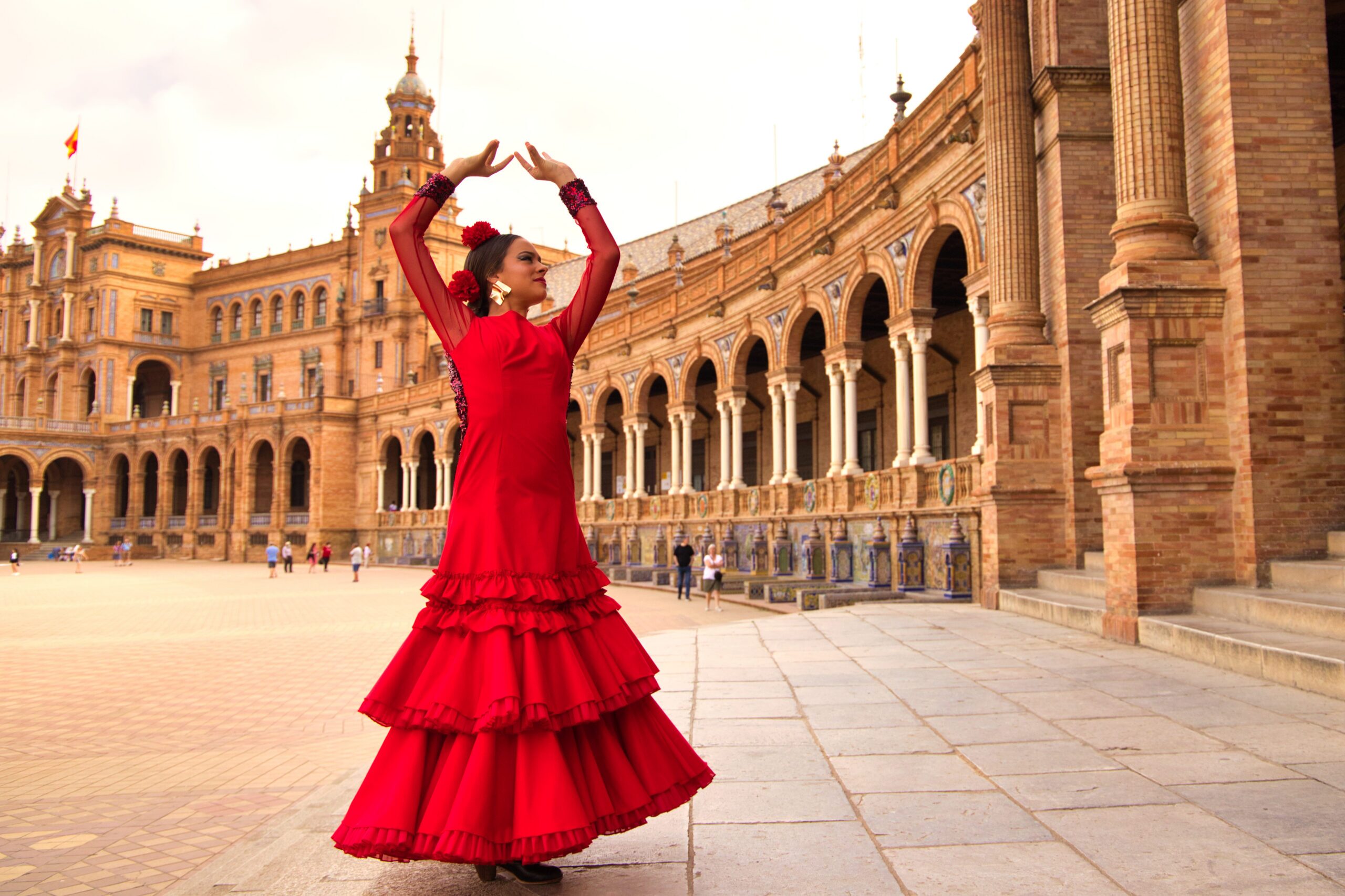 Beautiful teenage woman dancing flamenco in a square in Seville, Spain. She wears a red dress with ruffles and dances flamenco with a lot of art. Flamenco cultural heritage of humanity