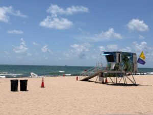 Sandy beach with waves and a large lifeguard stand.
